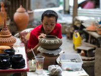 woman detailing traditional Thai clay bowl-vase